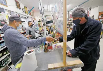  ?? LUIS SÁNCHEZ SATURNO/THE NEW MEXICAN ?? Rosalio Antonio Merino checks out Daniel Smith at Kelly’s Liquor Barn on Thursday.