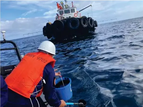  ?? (Reuters) ?? The coastguard collect samples yesterday from a massive oil slick off the northeast coast of the Philippine­s