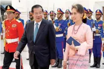  ?? AFP FILE PHOTO ?? WALK WITH ME
Myanmar’s then-state counselor Aung San Suu Kyi (right) and Cambodia’s then-prime minister Hun Sen walk past honor guards during her visit to the Peace Palace in the Cambodian capital Phnom Penh on April 30, 2019.