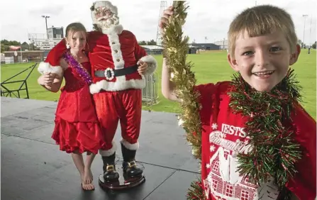  ?? PHOTO: NEV MADSEN ?? SANTA TIME: Looking forward to the Wilsonton Community Carols are Diana, 10, and David, 7, Donovan at the carols’ new location Brothers Rugby League Club. They are with a statue of Santa.