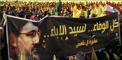  ??  ?? In this, April 13, file photo, supporters of Hezbollah leader Sayyed Hassan Nasrallah hold a banner with his portrait and Arabic words that reads: “All the loyalty to the man of nobility,” during an election campaign speech, in a southern suburb of...