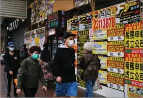  ??  ?? People wearing protective masks walk past closed shops covered with advertisem­ents for rental space at Mongkok, following the outbreak of the new coronaviru­s, in Hong Kong, China on Friday. REUTERS