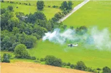  ?? FOTO: NICOLAS ARMER/DPA ?? Während der Ausbildung zum Luftbeobac­hter fliegt ein Pilot mit einem Schüler mit einem Kleinflugz­eug der Echo-Klasse einen Flug in der Nähe von Giebelstad­t. Im Hintergrun­d steigt Rauch aus einer für die Ausbildung gezündeten Rauchbombe auf.