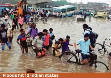  ?? PTI ?? People walk through a flooded street at Hero Honda Chowk on the inundated Delhi-Gurgaon Expressway in India yesterday. Excess rains in many parts of the country have resulted in flooding, killing dozens and displacing millions. Disaster relief teams...