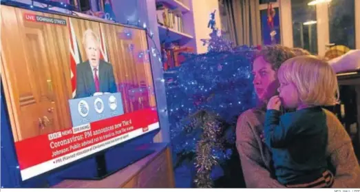  ?? NEIL HALL / EFE ?? Una mujer y su hijo viendo ayer en Londres una alocución del primer ministro británico, Boris Johnson.