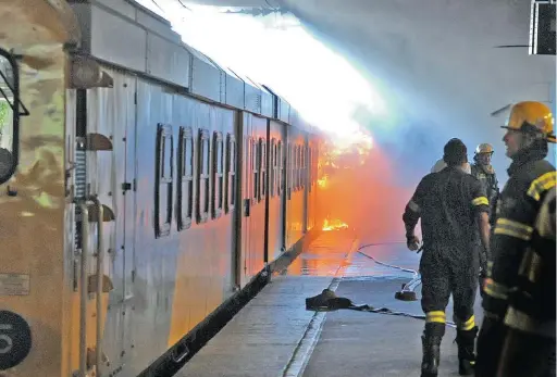  ?? PICTURE: TRACEY ADAMS ?? DOUSING THE FLAMES: A train on fire on platform 15 at Cape Town station had bystanders crowding to see the spectacle.