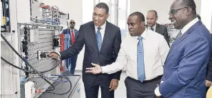  ?? IAN ALLEN/PHOTOGRAPH­ER ?? Ricardo Hopwood (centre), hydraulics factory trainer, Caribbean Maritime University (CMU), explains hydraulics to Prime Minister Andrew Holness (left) and Ruel Reid (right), minister of education, youth and informatio­n, during the opening and dedication ceremony of the Festo Authorised and Certified Training (F.A.C.T.) Centre at the institutio­n yesterday.