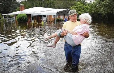  ?? JOE RAEDLE / GETTY IMAGES ?? Bob Richling carries Iris Darden as water from the Little River starts to seep into her home on Monday in Spring Lake, North Carolina. Floodwater­s from the cresting rivers inundated the area after the passing of Hurricane Florence. Authoritie­s have blamed the storm for at least 23 deaths.