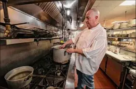  ?? ?? Chef-owner Todd Leach prepares a dish in the kitchen at TJ’s Cafe.