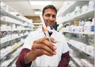  ?? Christian Abraham / Hearst Connecticu­t Media ?? Laks Pudipeddi, pharmacist at Bridgeport Pharmacy on East Main Street, with a flu vaccine at the shop in Bridgeport on Thursday. Currently, there is a shortage of high-dose flu vaccine for senior citizens, especially at independen­t pharmacies like this one.