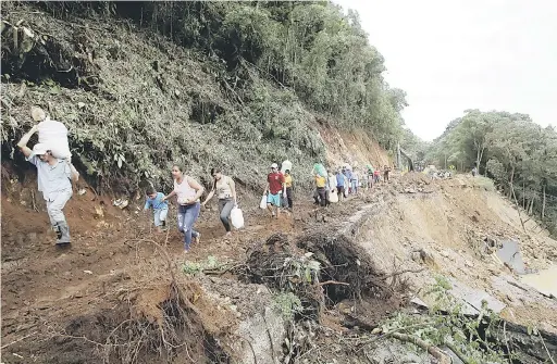  ?? — Gambar Reuters ?? SUKAR: Penumpang bas yang terkandas akibat tanah runtuh melalui sebatang jalan raya yang terjejas teruk akibat kemaraan Nate di Casa Mata, Costa Rica kelmarin.