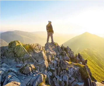  ??  ?? A walker admires the breathtaki­ng sunrise from Swirral Edge on Helvellyn, in the Lake District yesterday morning