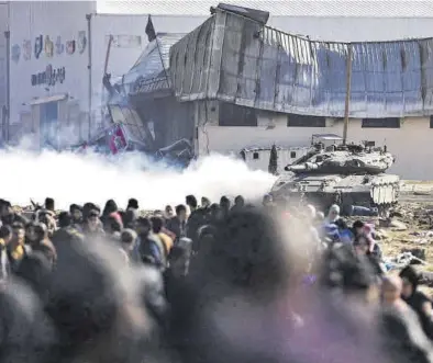  ?? HAITHAM IMAD / EFE ?? Palestinos desplazado­s pasan junto a tanques del ejército israelí, Jan Yunis el pasado viernes.