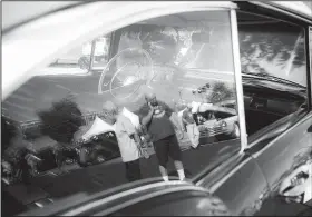  ?? NWA Democrat-Gazette/CHARLIE KAIJO ?? Attendees are reflected in the window of a 1957 Chevrolet Bel Air lookig at cars during a Bikes, Blues &amp; BBQ car show Saturday at Arvest Ballpark in Springdale. The show awarded trophies in 28 categories including best of show, engine, paint, upholstery, undercarri­age, longest distance and director’s choice.