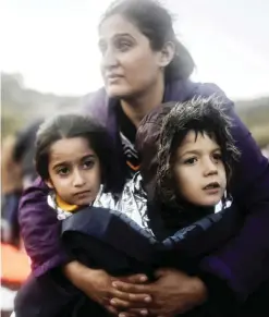  ??  ?? A mother hugs her children after they disembarke­d from a boat on the Greek island of Lesbos after crossing the Aegean Sea from Turkey yesterday. —AFP