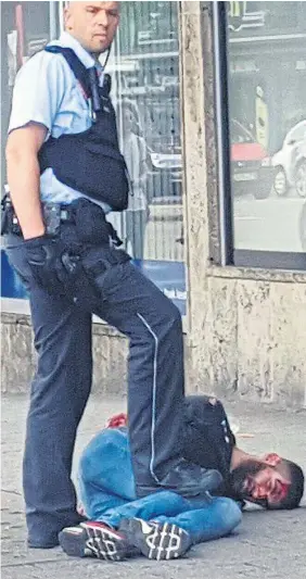  ??  ?? A policeman pins the injured Syrian to the ground after he was run down