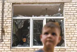  ?? DAVID GOLDMAN AP ?? A worker clears debris inside as Tikhon Pavlov, 11, walks past the rocket-damaged Kramatorsk College of Technologi­es and Design in eastern Ukraine.