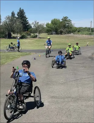  ?? JUSTIN COUCHOT — ENTERPRISE-RECORD ?? Campers and coaches finish up a bike ride on hand-pedal bikes on the first day of the Ability First sports camp on Thursday at SkyLake Ranch in Durham.