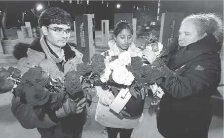  ?? NICK BRANCACCIO ?? Rupesh Vagheshwar­i, Deepthi B. Jampana and Eva Kratochvil prepare roses for the National Day of Remembranc­e and Action on Violence Against Women event at the U of W Thursday. About 100 people attended the vigil to mark the anniversar­y of the 1989 Montreal Massacre.