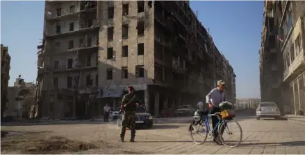  ?? (Photo by Nataliya Vasilyeva, AP) ?? A man crosses the road with his bicycle in what was once a rebel-controlled area in Aleppo, Syria, Tuesday, Sept. 12, 2017. The recapture of eastern Aleppo in December 2016, one of the deadliest episodes of the Syrian civil war, was a landmark victory...