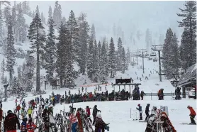  ?? Chloe Shrager/The Chronicle ?? Lift lines fill Wednesday as snow flurries fall at the base of the Alpine ski area at Palisades Taho. Skiers rejoiced as a storm covered Lake Tahoe.