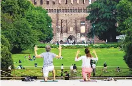  ?? PIER MARCO TACCA GETTY IMAGES ?? A couple practice yoga Wednesday at Sempione Park in Milan, Italy. Italy is slowly easing some coronaviru­s restrictio­ns.