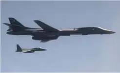  ??  ?? IN FLIGHT: This US Air Force handout photo shows A US Air Force B-1B Lancer, flanked by Republic of Korea Air Force F-15K Slam Eagles, dropping a 2,000 pound live munition at Pilsung Training Range, South Korea as part of a show of force mission in...