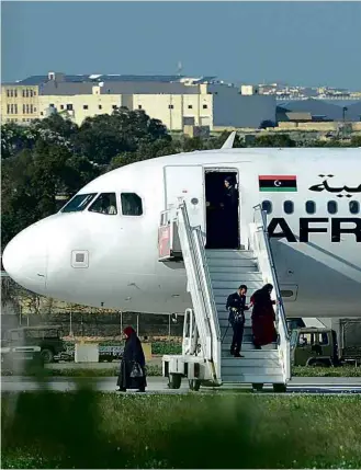  ?? Matthew Mirabelli/AFP ?? Tripulante ajuda passageira feita refém a desembarca­r de avião no aeroporto de Malta