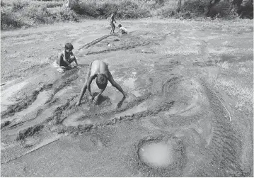  ?? SAURABH DAS / THE ASSOCIATED PRESS ?? Children play on farmland destroyed by asbestos sediments in Roro, India, in 2014. More than 50 countries have banned all forms of asbestos, but the industry has found new markets in developing countries, particular­ly in Asia.