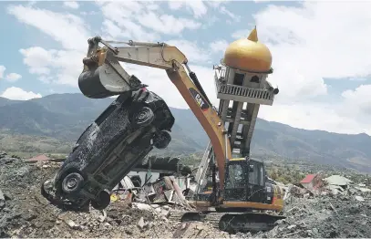  ?? Picture:Reuters ?? PICKING UP PIECES. An excavator removes a damaged car next to the debris of a mosque damaged by an earthquake in the Balaroa neighbourh­ood in Palu, Central Sulawesi, Indonesia.