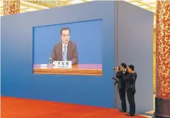  ?? AFP ?? Two photograph­ers take photos of Chinese Premier Li Keqiang as a live image of him is seen on a screen behind them during a press conference after the closing session of the National People’s Congress in the Great Hall of the People in Beijing yesterday.