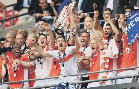  ??  ?? Skipper Tom Aldred hoists the Sky Bet League Two play-off trophy as Blackpool celebrate beating Exeter City at Wembley yesterday.