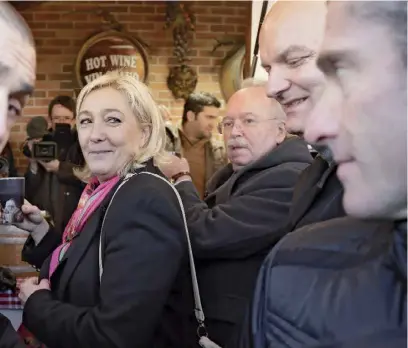  ??  ?? Marine Le Pen, en visite au marché de Noël des ChampsElys­ées, le 9 décembre 2013. Derrière elle (avec des lunettes), son candidat à la mairie de Paris, Wallerand de Saint-Just