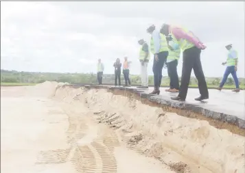  ??  ?? Ministers of Public Infrastruc­ture David Patterson (at right) and Annette Ferguson (at centre) inspect works where the old airport runway meets the new expanded one currently built up with sand. (Photo by Keno George)