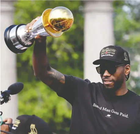  ?? MOE DOIRON/REUTERS ?? Toronto Raptors star Kawhi Leonard hold his MVP trophy from the NBA Finals during the Raptors’ victory parade last week. Leonard will soon become a free agent, though it doesn’t look like Ontario’s income tax situation will be a big factor in his decision whether to re-sign or go.