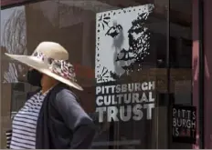  ?? Steph Chambers/Post-Gazette ?? A masked woman walks past the Pittsburgh Cultural Trust offices Thursday in Downtown’s Cultural District. For the first time in 35 years, the Cultural Trust has a $6 million deficit.
