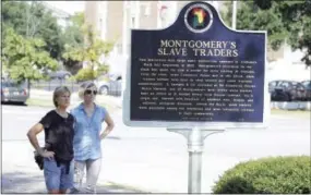  ?? JAY REEVES — THE ASSOCIATED PRESS ?? In this photo taken Thursday tourists Nancy Lange, left, and daughter Teresa Lange read a memorial marker about old slave markets in Montgomery, Ala. The same group that erected the marker is planning a memorial and museum to black lynching victims in...