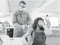  ?? LYNNE SLADKY/AP ?? Leanne Montenegro, 21, covers her eyes to avoid the sight of needles while she receives the Pfizer COVID-19 vaccine. Although any adult in Florida is now eligible to receive vaccines, employers are recommendi­ng not requiring employees to get their shots.