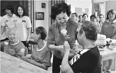  ??  ?? Kong presents a rose to a resident at Miri Home for the Aged.