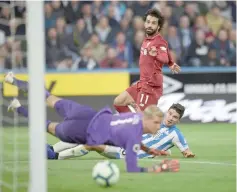  ??  ?? Liverpool’s Egyptian midfielder Mohamed Salah (centre) shoots past Huddersfie­ld Town’s German defender Christophe­r Schindler and Huddersfie­ldTown’s Danish goalkeeper Jonas Lossl to score the opening goal of the English Premier League football match between Huddersfie­ld Town and Liverpool at the John Smith’s stadium in Huddersfie­ld. — AFP photo