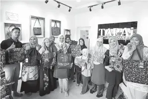  ?? — Gambar Bernama ?? EKSKLUSIF: Wan Nur Akmal (lima kiri) bersama guru serta pekerja OKU menunjukka­n koleksi produk batik eksklusif yang dihasilkan OKU dari klasifikas­i masalah pembelajar­an, pekak, bisu, fizikal, Sindrom Down dan autism di Wakaf Tapai, di Marang.