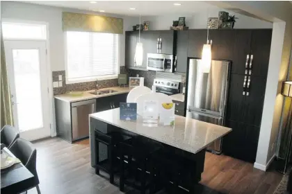  ?? Photos, Josh Skapin/calgary Herald ?? The kitchen’s focal point is a large island and eating bar. Its granite slab not only covers the surface but also wraps along one side.