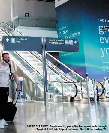  ??  ?? GOT TO GET AWAY: People wearing protective face masks walk through Terminal 2 in Dublin Airport last week. Photo: Brian Lawless/PA