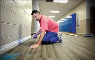  ?? NWA Democrat-Gazette/DAVID GOTTSCHALK ?? Wilfredo Calderon, with Davis Flooring, fits a piece of LVT tile July 6 in the hallway at Woodland Junior High in Fayettevil­le. New tile is being put down in the hallways and cafeteria of the school. Northwest Arkansas school districts are busy working on facility improvemen­t projects while staff and students are away for the summer break.