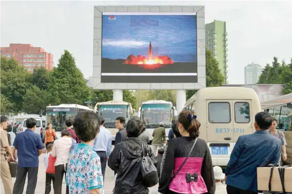  ?? — Reuters ?? North Koreans watch a news report showing North Korea’s Hwasong-12 intermedia­te-range ballistic missile launch on electronic screen at Pyongyang station in Pyongyang on Wednesday.