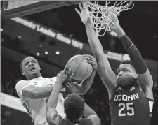  ??  ?? Memphis forward Precious Achiuwa, left, battles for a rebound Saturday with UConn’s Jalen Gaffney during their game at the FedExForum in Memphis, Tenn. Below, the Huskies’ Akok Akok, center, fouls the Tigers’ Alex Lomax, left, as UConn’s Josh Carlton closes in.