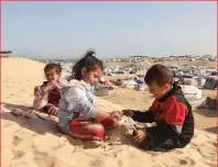  ?? ?? (Centre) Children play on a sand dune overlookin­g a camp for displaced people in Rafah.