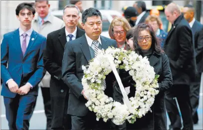  ?? Michael Dwyer ?? The Associated Press The father of Lingzi Lu, Jun Lu, foreground left, and her aunt Helen Zhao, foreground right, carry a wreath Sunday ahead of the family of Martin Richard, background from left, Henry, Bill, Denise and Jane, partially hidden, during...