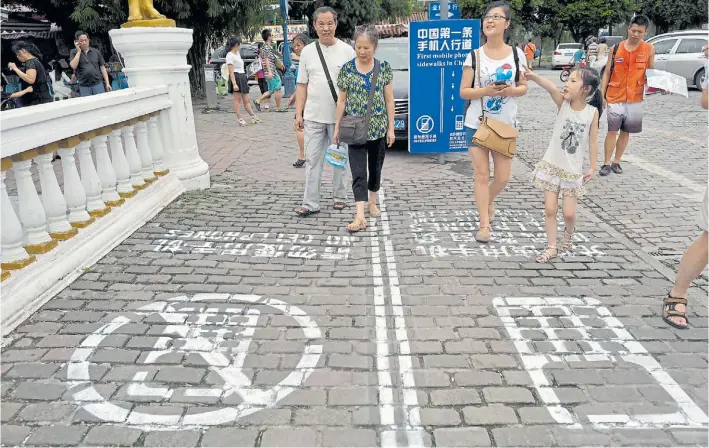  ?? AP PHOTO ?? El municipio chino de Chongqing copió la idea de un programa de tevé estadounid­ense y desde 2014 separa en carriles diferentes a paseantes con celular y sin él, para alentar a no tuitear mientras se camina.