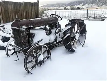  ?? JON HAMMOND / FOR TEHACHAPI NEWS ?? A 1922 Fordson tractor is dusted in snow, with the Tehachapi Mountains south of Highline Road visible below clouds in the background.